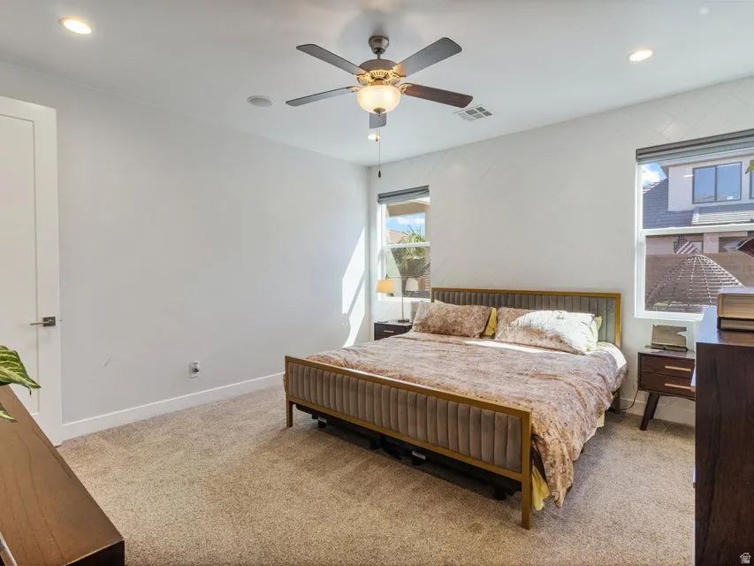 Carpeted room featuring a ceiling fan with integrated lighting, recessed lighting, and two windows