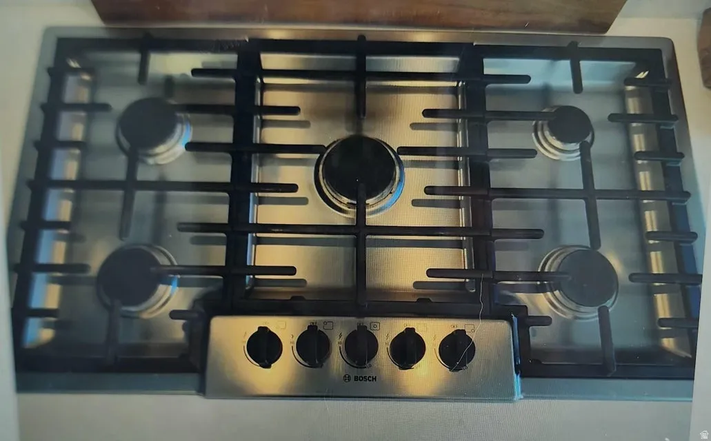 Stainless steel gas cooktop with five burners and cast-iron grates