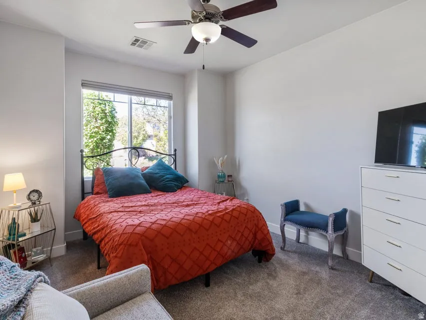 Spacious room featuring neutral carpeting, a large window, and a ceiling fan with integrated lighting
