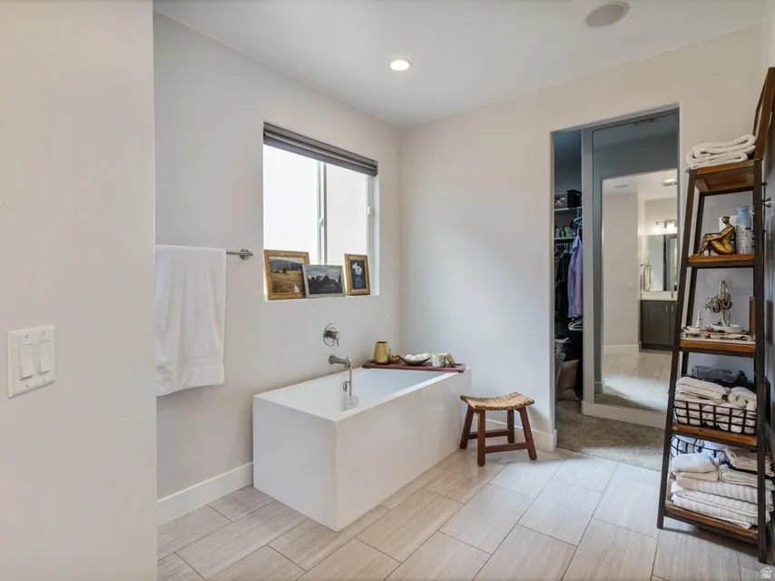 Modern bathroom featuring a freestanding soaking tub, large format tile flooring, and recessed ceiling lighting