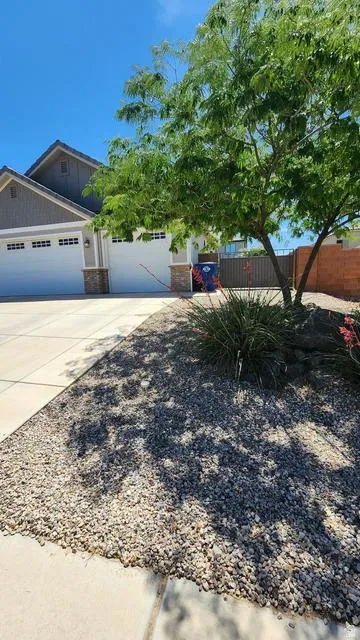 Residential exterior featuring a two-car garage, stone accents, and a low-maintenance gravel landscape