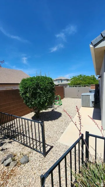 Side yard featuring a rock-covered landscape, block wall perimeter, and a compact shrub