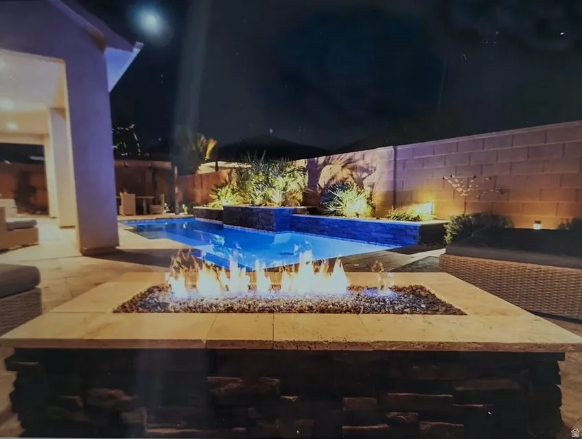 Patio area featuring a stone-clad fire pit with a light-colored countertop and a gas flame