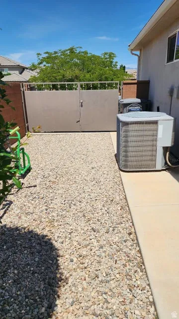 Gated side yard featuring a gravel bed and concrete walkway