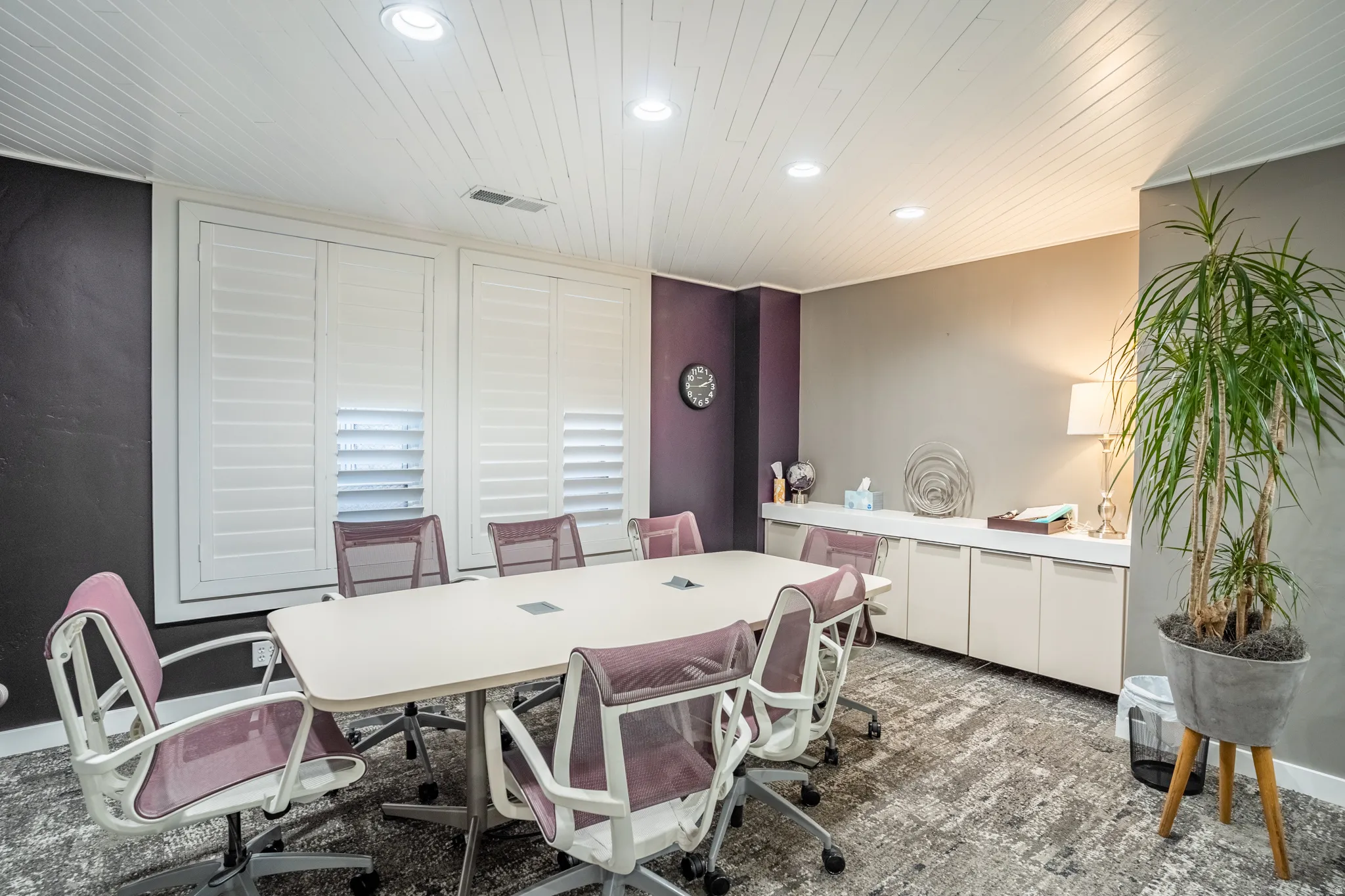 Conference room featuring a large central table, built-in cabinetry, recessed lighting, white shutter window treatments, and textured carpet flooring
