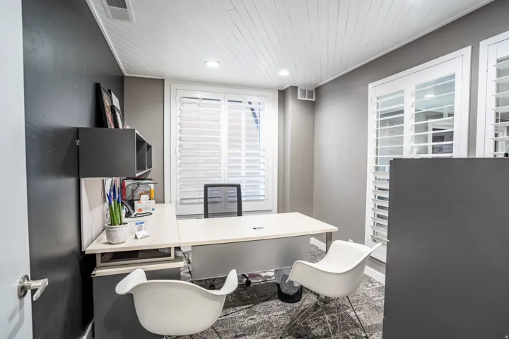 Room with textured gray walls, white plantation shutters, and a wood-plank ceiling