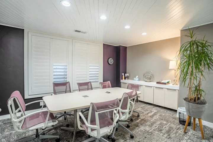 Conference room featuring a large central table, built-in cabinetry, recessed lighting, white shutter window treatments, and textured carpet flooring