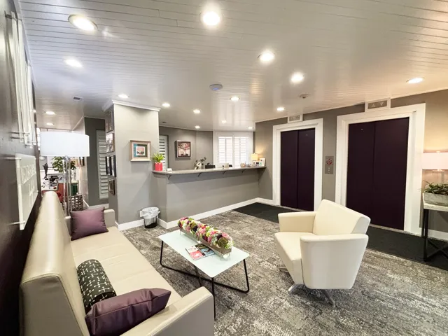 Lobby reception area featuring two elevator entrances with dark doors and light trim, a reception counter, and recessed lighting