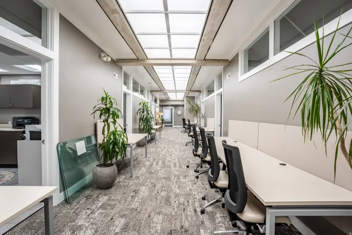 Hallway workspace featuring an overhead skylight system, wood-finish ceiling beams, and light gray wall paint