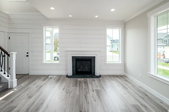 Living space featuring a shiplap accent wall, a white mantel fireplace with dark stone surround, and wood-finish flooring