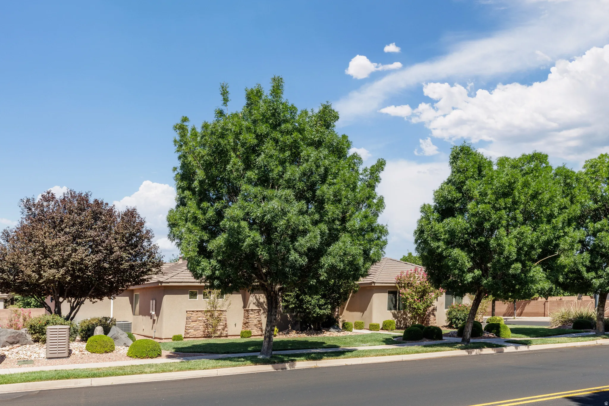 Front of home featuring mature trees and well established landscaping