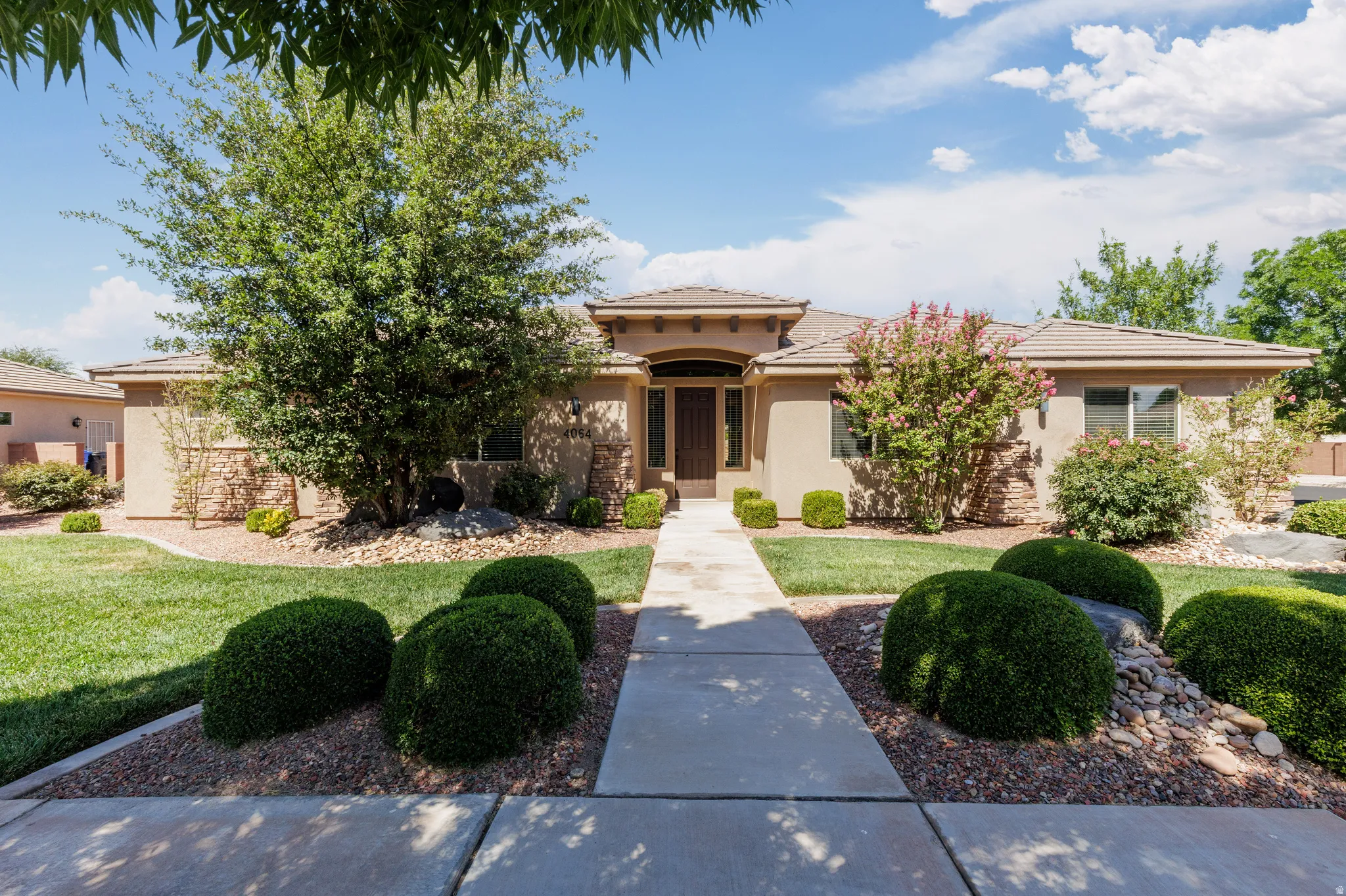 Front exterior showcasing a stucco finish, stone accents, and a tile roof