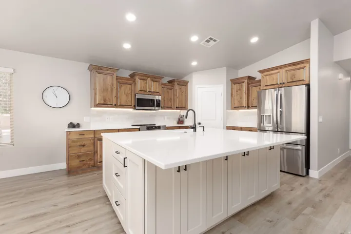 Modern kitchen featuring stainless steel appliances, wood-finish cabinetry, quartz countertops, white subway tile backsplash, and recessed lighting