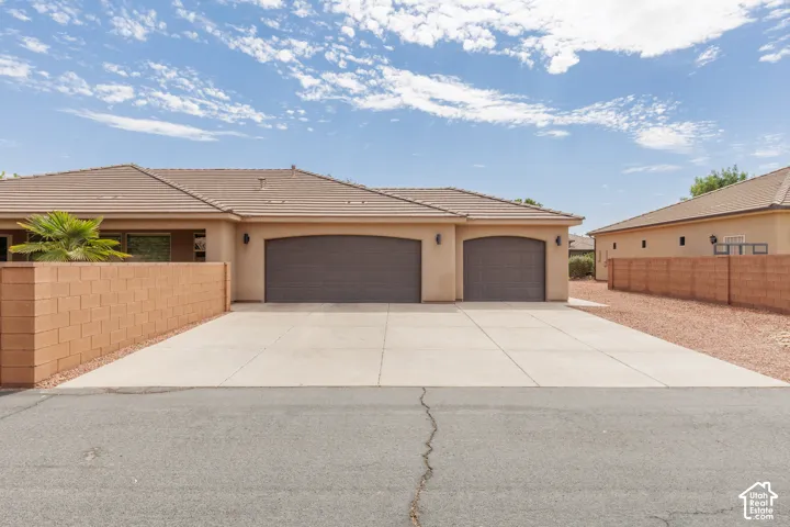 Single-story residence featuring a tan stucco exterior and a 3-car concrete driveway and RV parking