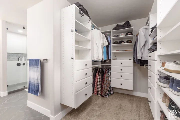 Custom closet organization system featuring white cabinetry with black hardware, extensive shelving, integrated drawer storage, and multiple hanging rods