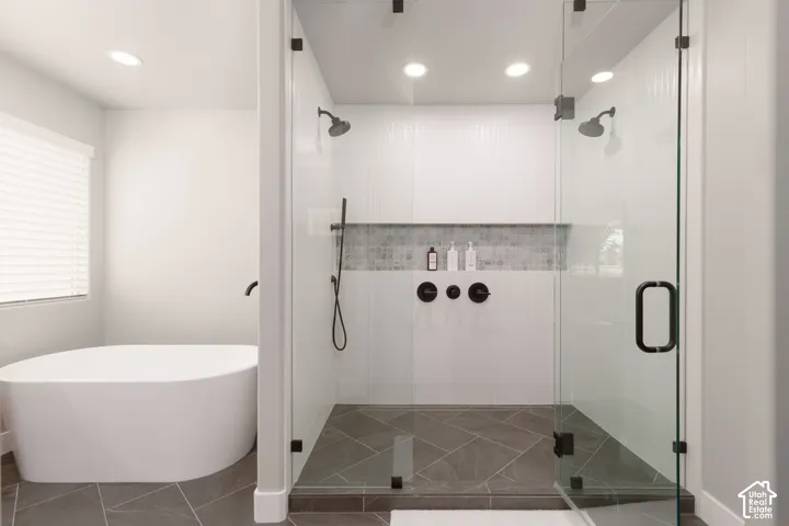 Primary ensuite bathroom with custom walk-in glass enclosure shower with dual shower heads large niche and soaking tub