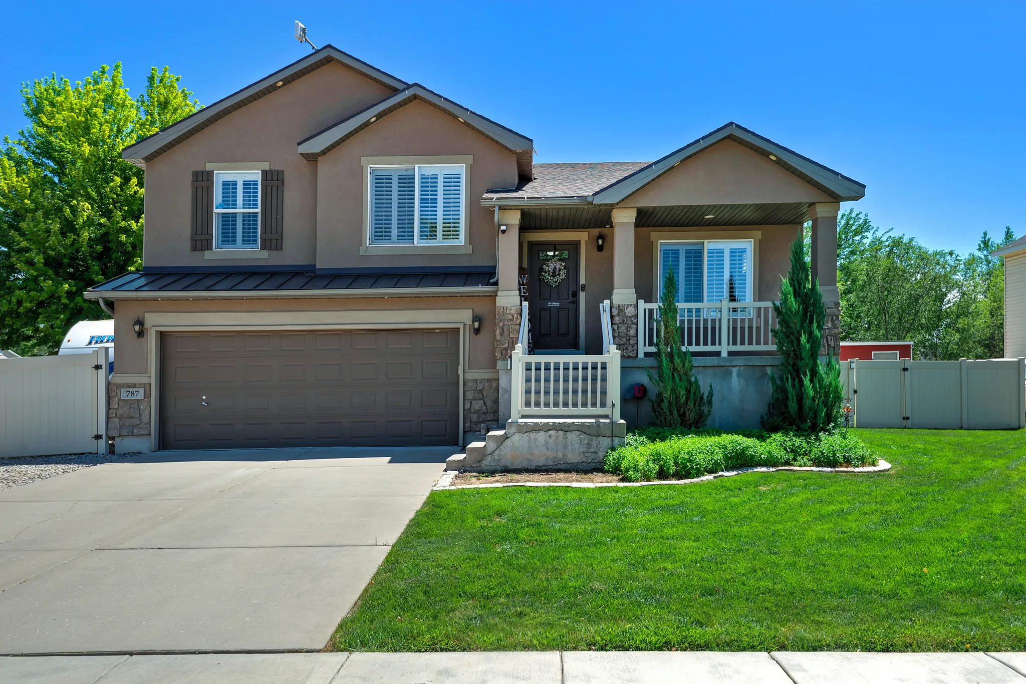 Two-story stucco residence featuring a covered front porch with stone accents and white railings