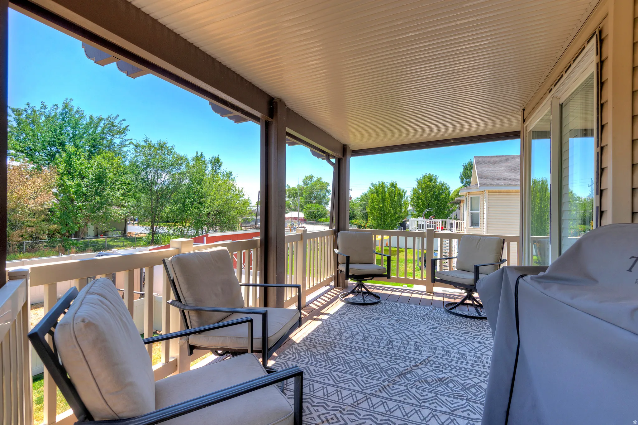 Covered outdoor deck featuring composite decking, white railing, and a tongue-and-groove ceiling