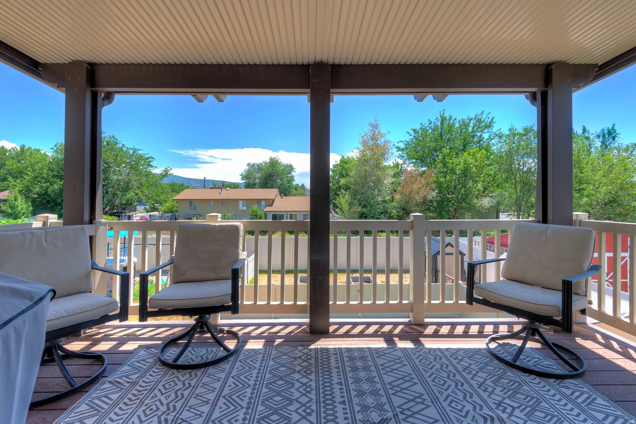 Covered outdoor deck featuring wood-finish decking and a light-colored railing system