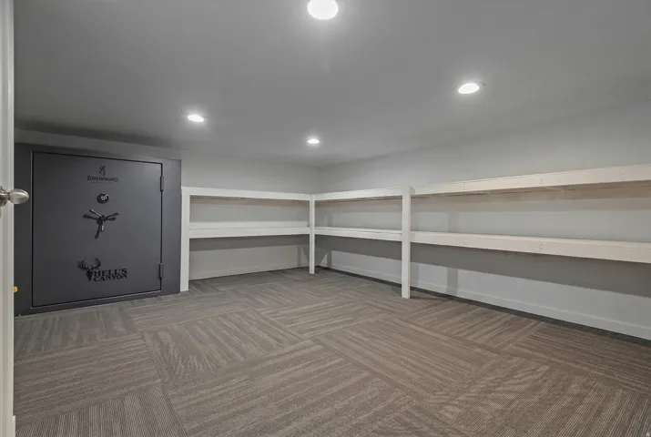 Dedicated storage space featuring a built-in safe, extensive shelving, recessed lighting, and patterned carpet flooring