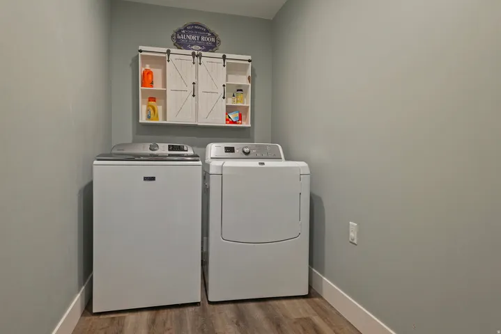 Dedicated laundry area featuring wood-finish flooring and light gray walls