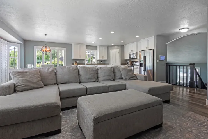 Open-concept living space featuring wood-finish flooring, recessed lighting, and a kitchen with white cabinetry and stainless steel appliances