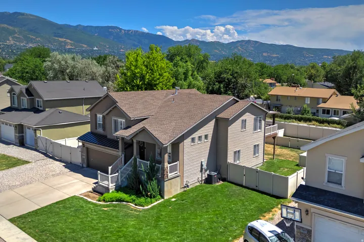 Two-story residence featuring a covered front porch, attached garage with asphalt driveway, and a fenced backyard