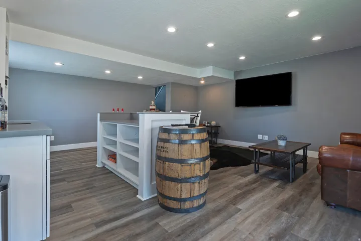 Spacious finished area featuring wood-finish flooring, recessed lighting, and a built-in bar with open shelving