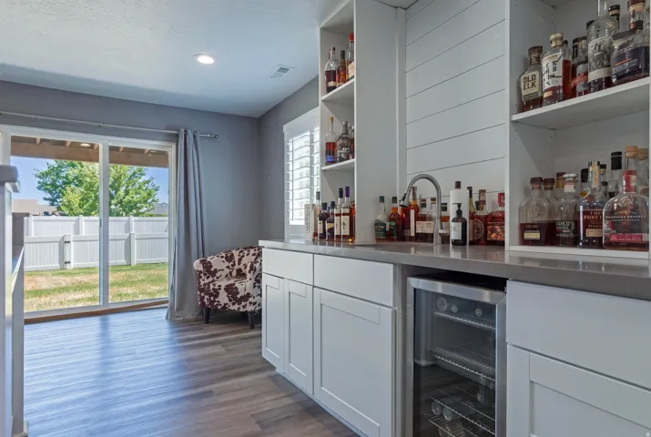 Built-in bar featuring white cabinetry, integrated beverage cooler, and open shelving
