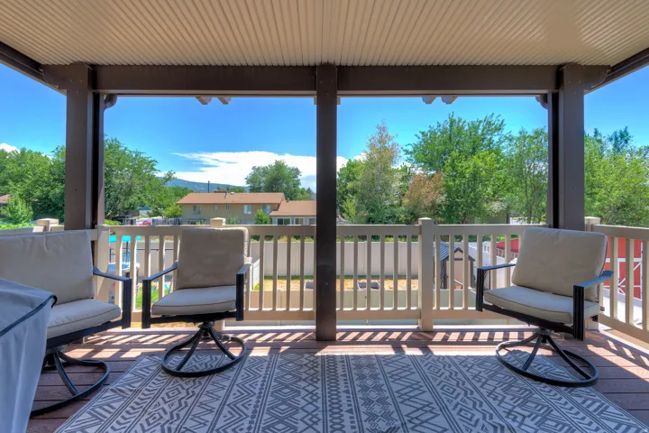 Covered outdoor deck featuring wood-finish decking and a light-colored railing system