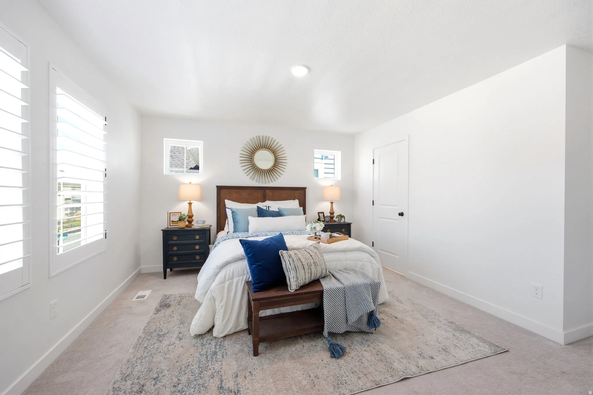 Bright bedroom featuring plantation shutters, carpet flooring, a built-in closet door, and contemporary white walls