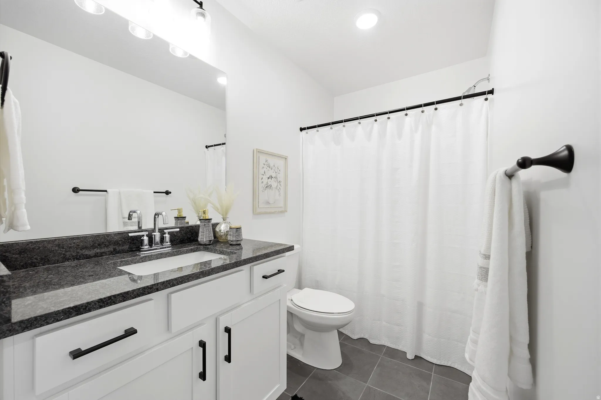 Bathroom featuring a white vanity with dark countertop, an integrated rectangular sink, and chrome faucet