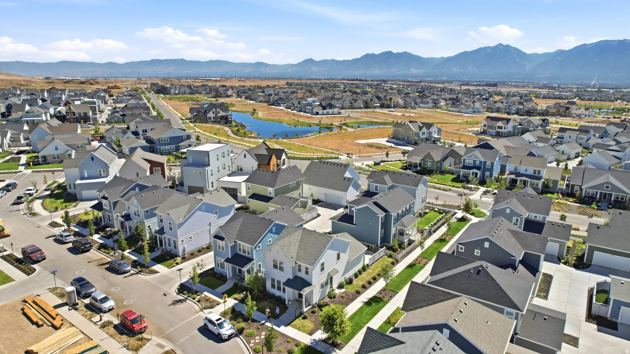 Aerial perspective of a developed residential community featuring diverse architectural styles and a prominent central pond