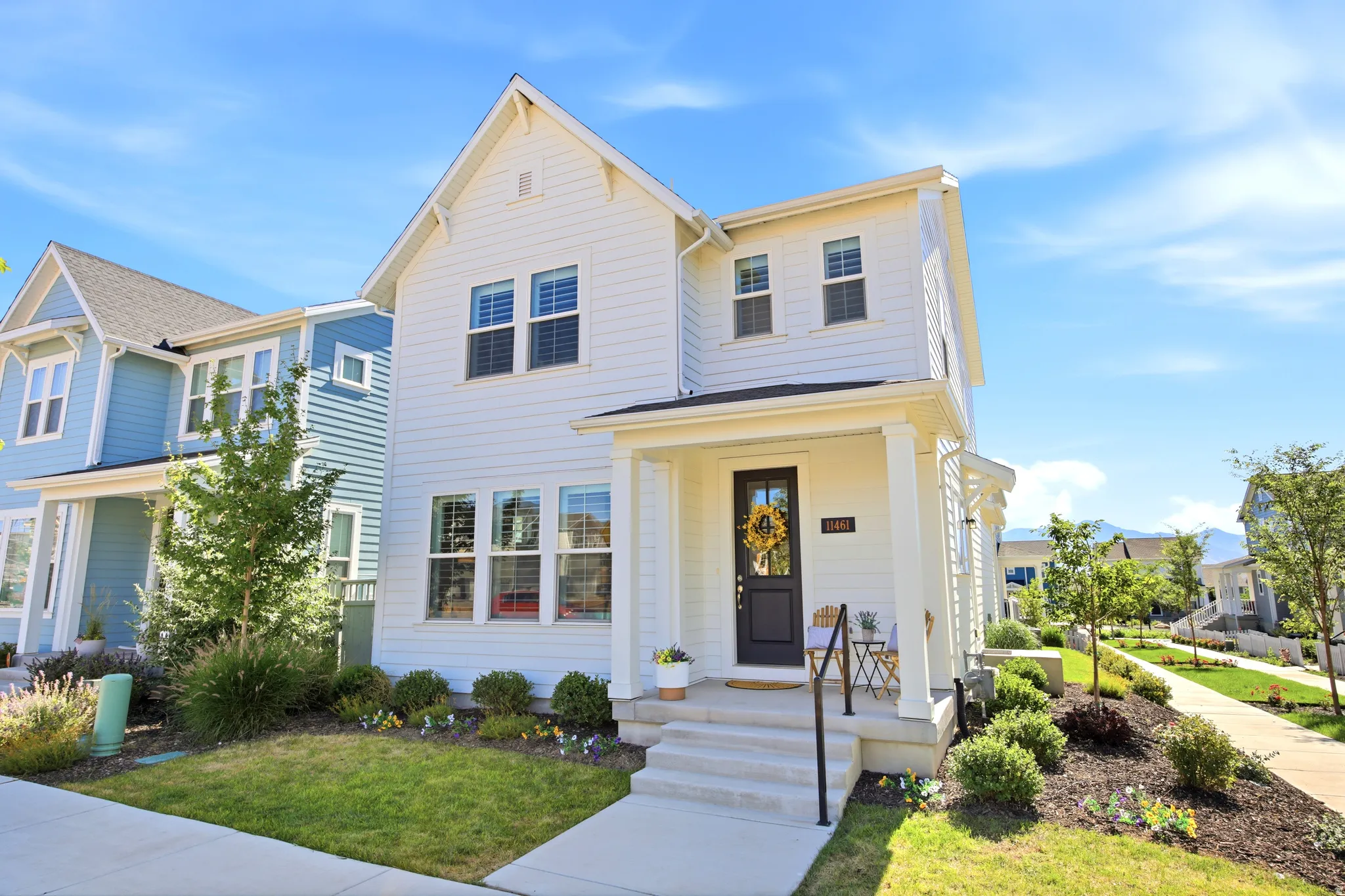 White two-story residence featuring a covered front porch, dark entry door, and multiple windows with white frames