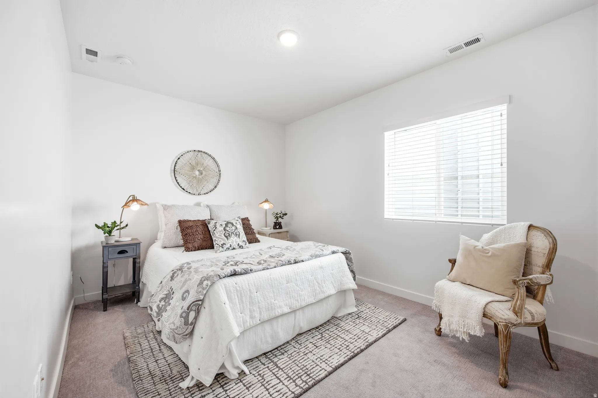 Bright bedroom with white walls and a single window featuring horizontal blinds