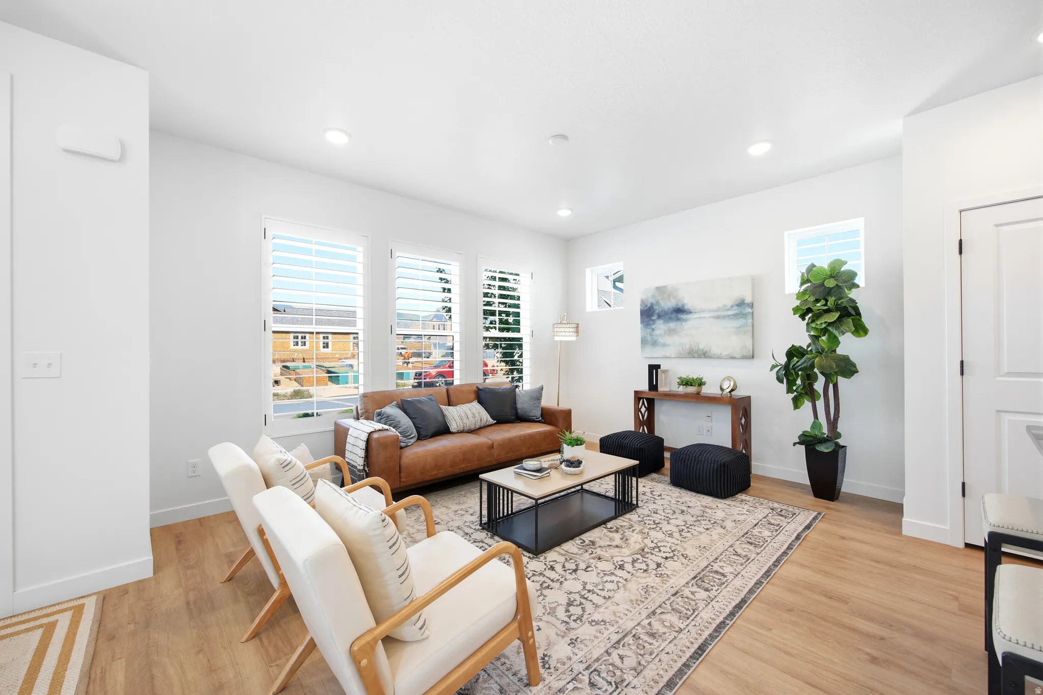 Bright living space featuring light wood-finish flooring, recessed lighting, and white walls