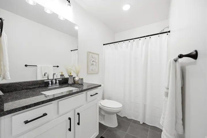 Bathroom featuring a white vanity with dark countertop, an integrated rectangular sink, and chrome faucet