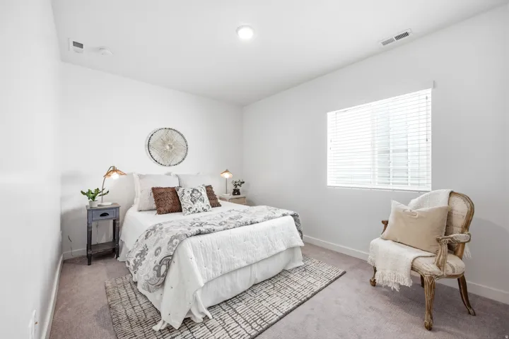 Bright bedroom with white walls and a single window featuring horizontal blinds
