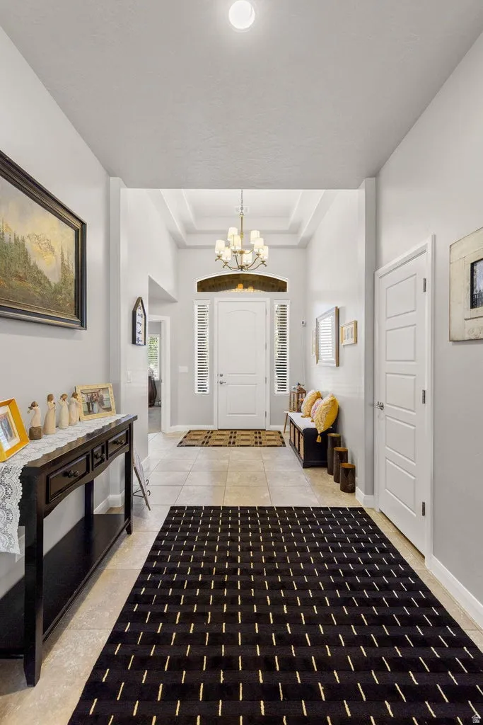 Grand foyer entrance featuring a coffered ceiling and a multi-arm chandelier