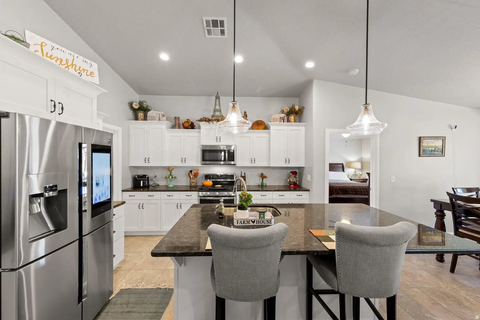 Kitchen featuring a large central island with seating, white cabinetry, dark countertops, and stainless steel appliances