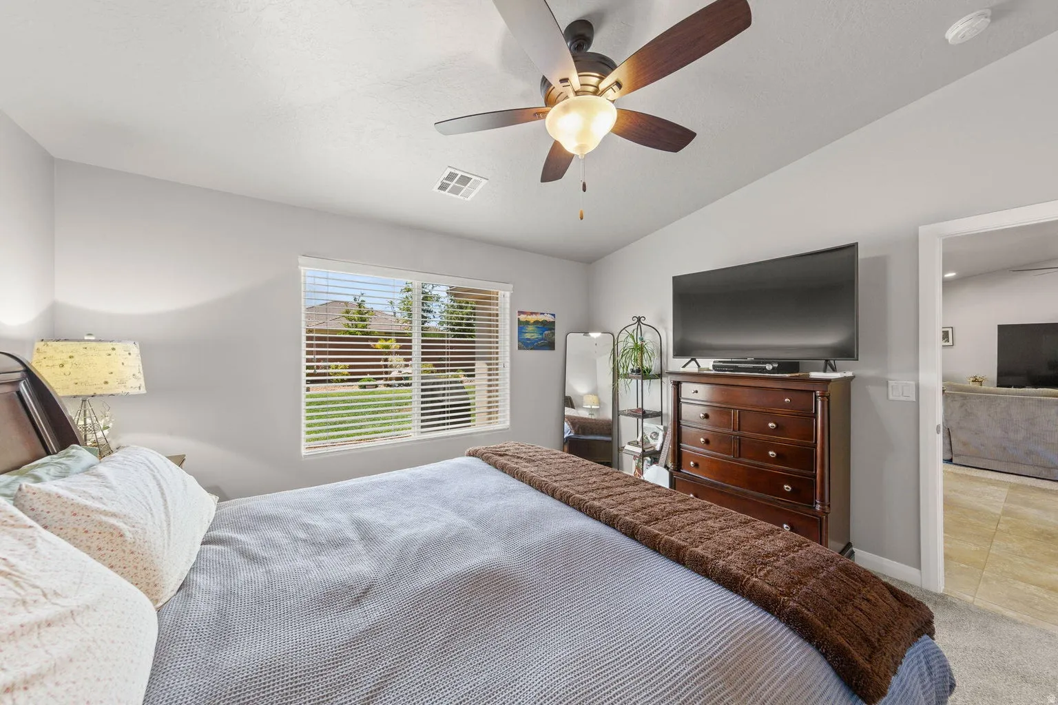 Interior space featuring light gray wall paint, a window with horizontal blinds overlooking a grassy exterior, and a ceiling fan with integrated lighting