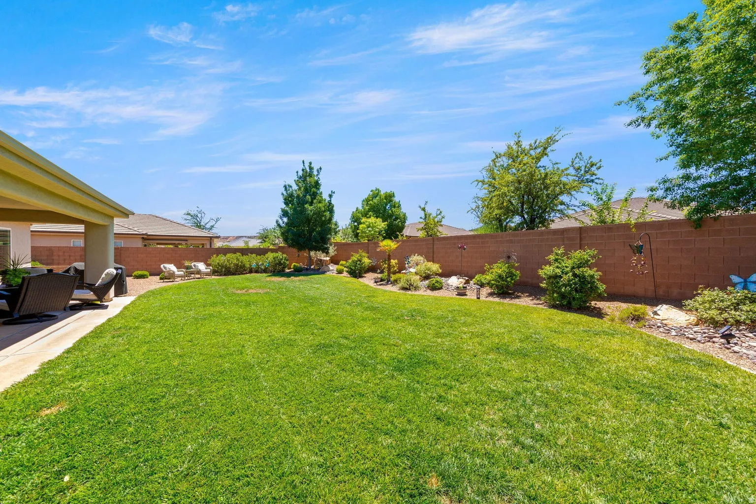 Spacious backyard featuring a manicured lawn, an extended patio, and a perimeter block wall