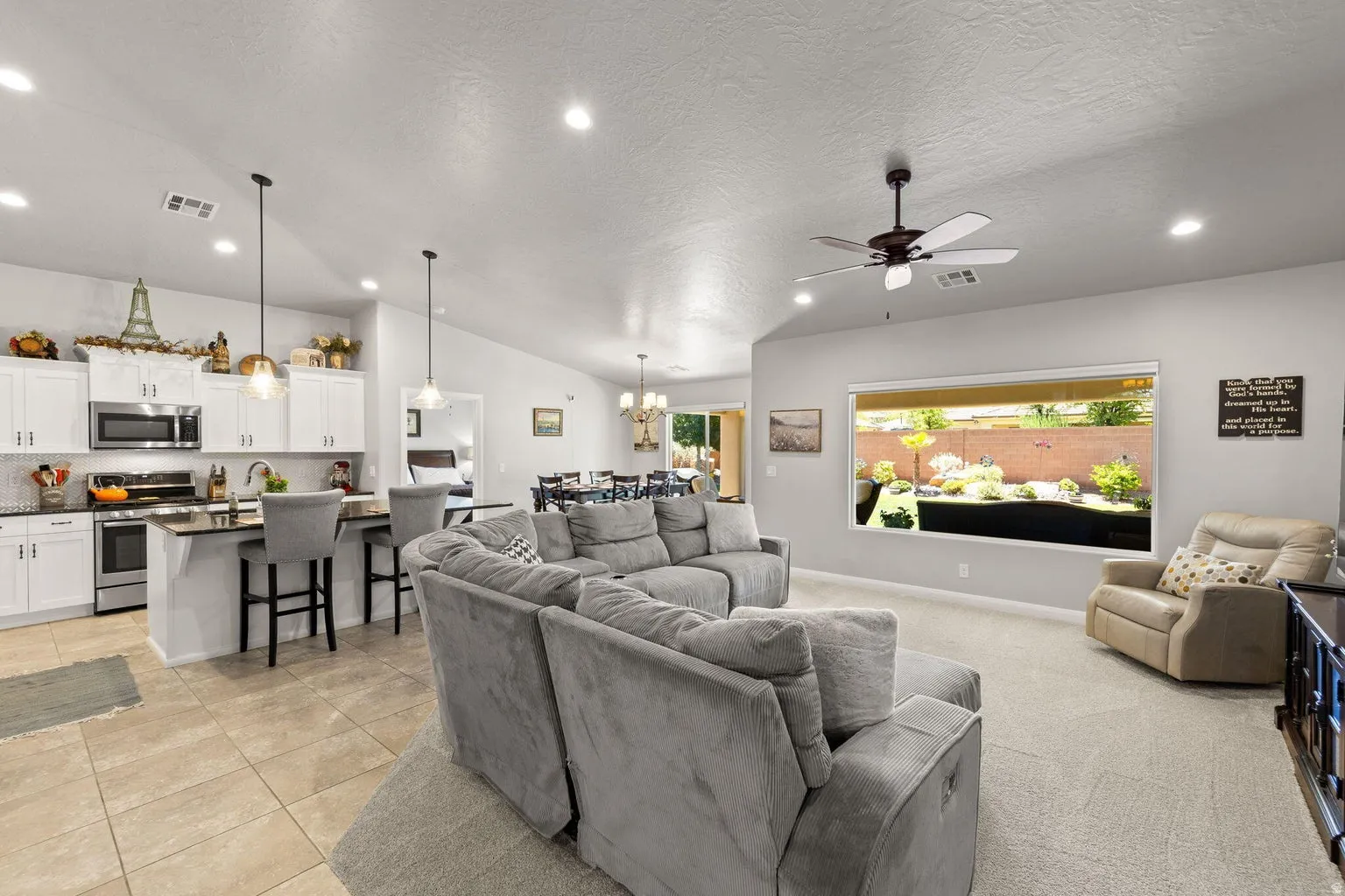 Open-concept living space featuring vaulted ceilings, recessed lighting, and a prominent window