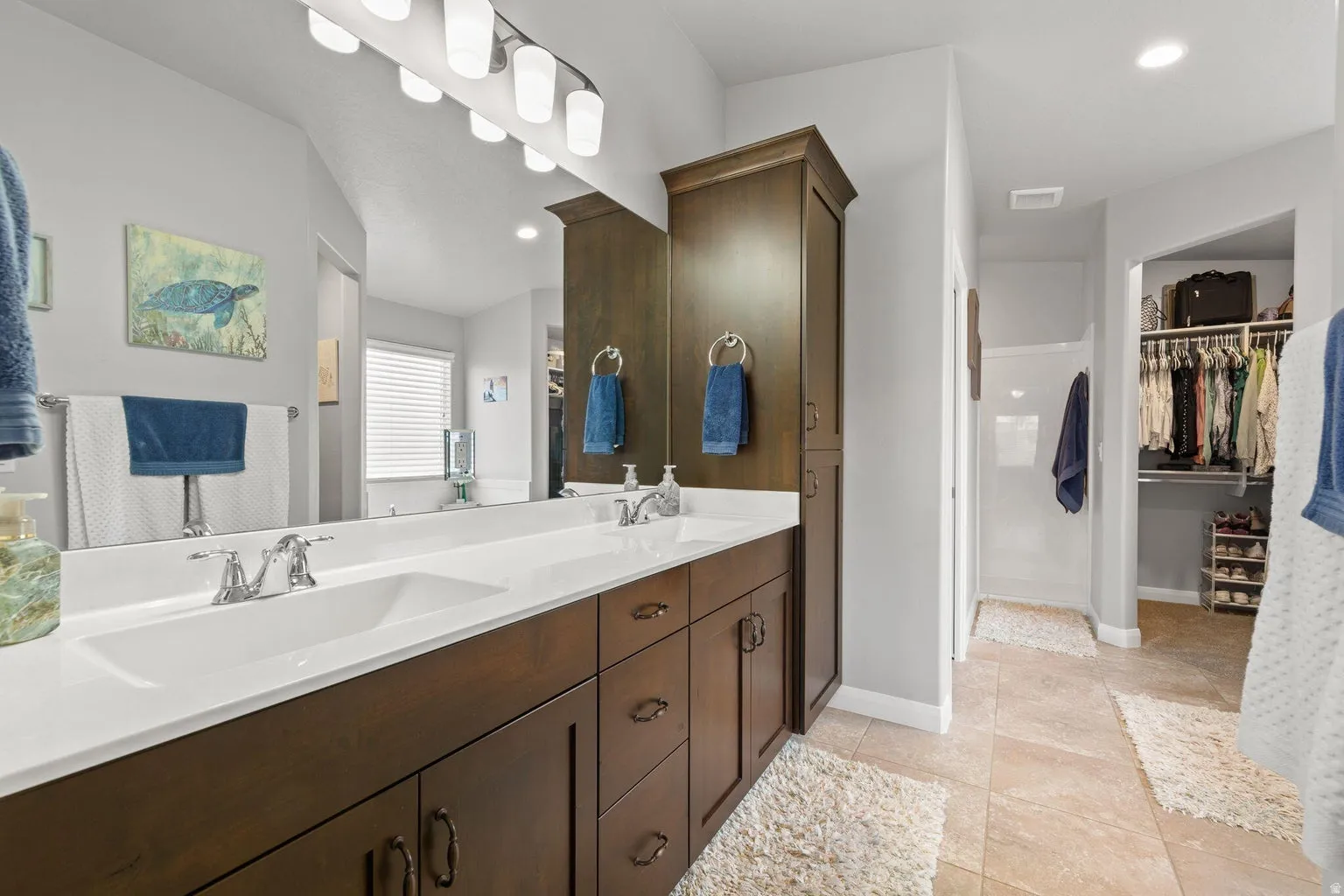Bathroom vanity featuring dual undermount sinks, chrome fixtures, and a white countertop