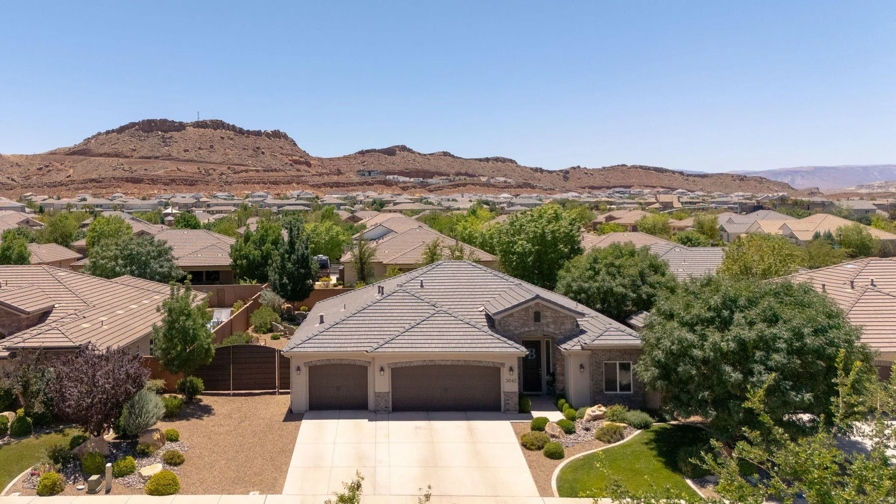 Single-story residence featuring a two-car garage, stone and stucco exterior, and a tiled roof