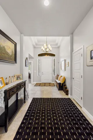 Grand foyer entrance featuring a coffered ceiling and a multi-arm chandelier