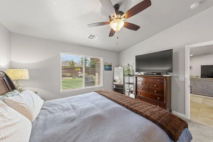 Interior space featuring light gray wall paint, a window with horizontal blinds overlooking a grassy exterior, and a ceiling fan with integrated lighting