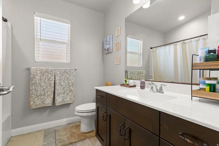 Bathroom featuring a single basin vanity with dark wood cabinetry, a white countertop, and a large wall-mounted mirror