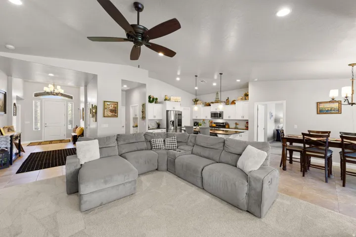 Expansive living area featuring vaulted ceilings, a ceiling fan, and carpet flooring
