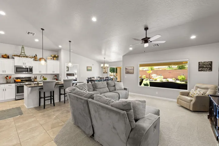 Open-concept living space featuring vaulted ceilings, recessed lighting, and a prominent window